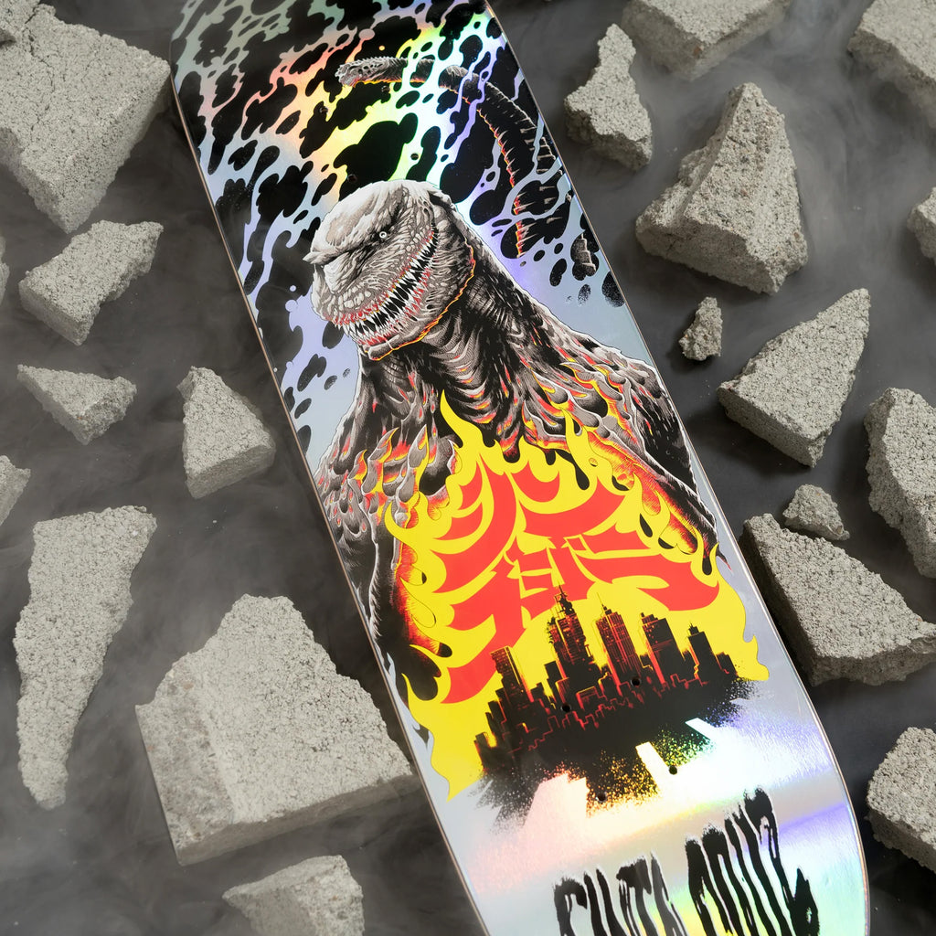 This SANTA CRUZ X GODZILLA SHIN KNOX FIREPIT skateboard deck by SANTA CRUZ features a captivating monster illustration inspired by Godzilla, engulfed in flames amidst a cityscape and rubble backdrop. Crafted from durable North American Maple, the deck boasts a stunning holographic sheen.