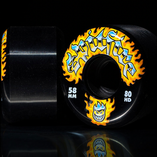 SPITFIRE 80HD CHROME VENOM CONICAL FULL 58MM skateboard wheels in black feature yellow flames, blue accents, "CONICAL FULL 58MM" text, and a grinning face logo—ideal for skaters who SKATE LIKE A GIRL.