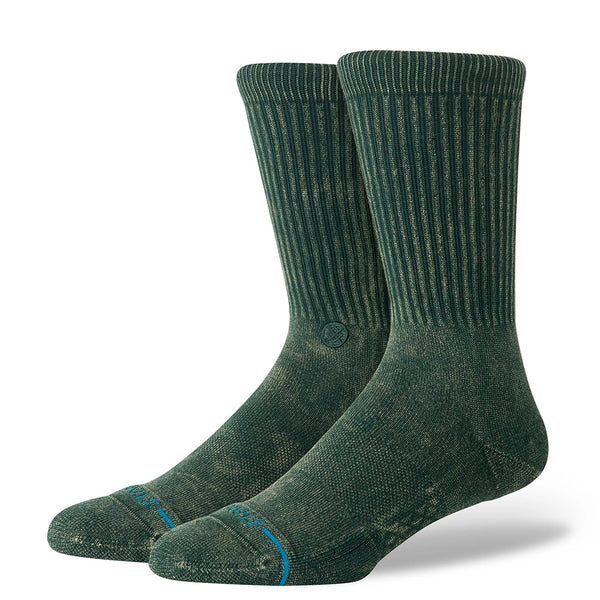 A pair of STANCE ICON DYED PINE socks in large, featuring a green hue, crew height, ribbed cuffs, and reinforced toes and heels in a soft cotton blend, displayed on a white background.