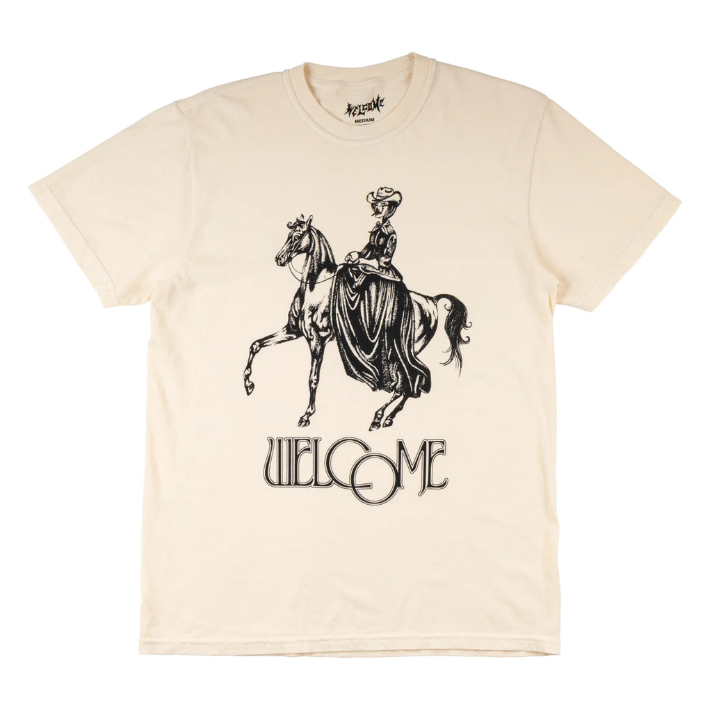 A WELCOME COWGIRL GARMENT-DYED TEE BONE with an image of a woman riding a horse.
