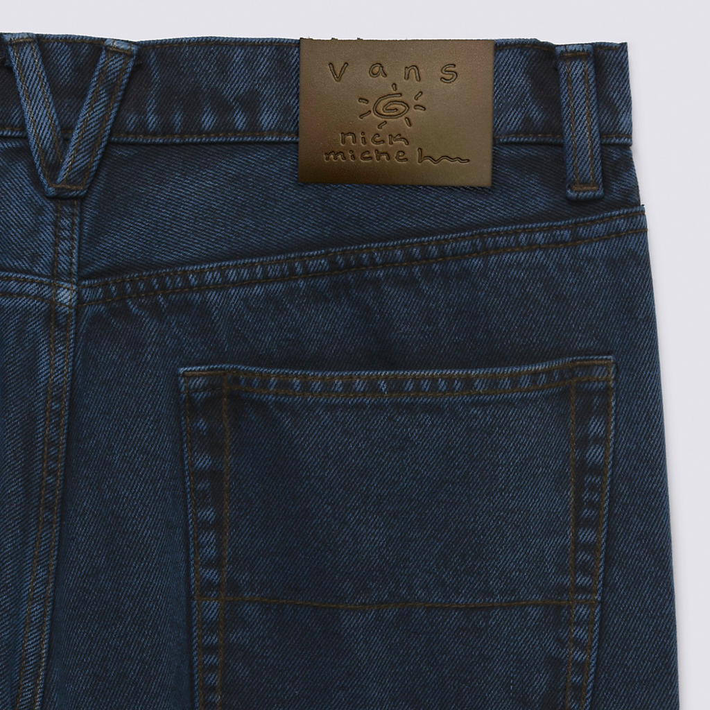 A close up of the brown leather patch on the back of the jeans that says "Vans Nick Michel" with a sunshine drawing"