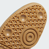 Close-up of a textured geometric pattern cupsole in brown rubber with circular grips and triangular details, inspired by the iconic ADIDAS SAMBA ADV Shoes in Blue Bird, Cloud White, and Gold Metallic.