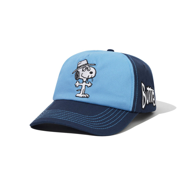The Butter Goods BUTTER X PEANUTS SPIKE 5 PANEL CAP NAVY / LIGHT BLUE is a cotton twill cap with panel design, featuring direct Snoopy embroidery on the front and "Butter" stitched on the side.
