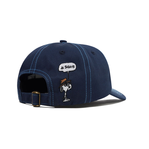 The Butter Goods BUTTER X PEANUTS SPIKE 5 PANEL CAP NAVY / LIGHT BLUE is a navy cotton cap with blue stitching and an embroidered Snoopy “Sigh” detail above the adjustable strap.