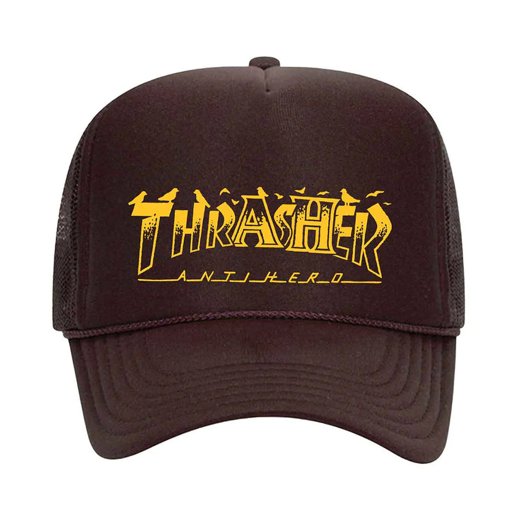 Brown mesh adjustable snapback hat with vibrant yellow "THRASHER x ANTI HERO PIGEON MAG TRUCKER HAT BROWN" logo artwork on the front by THRASHER.