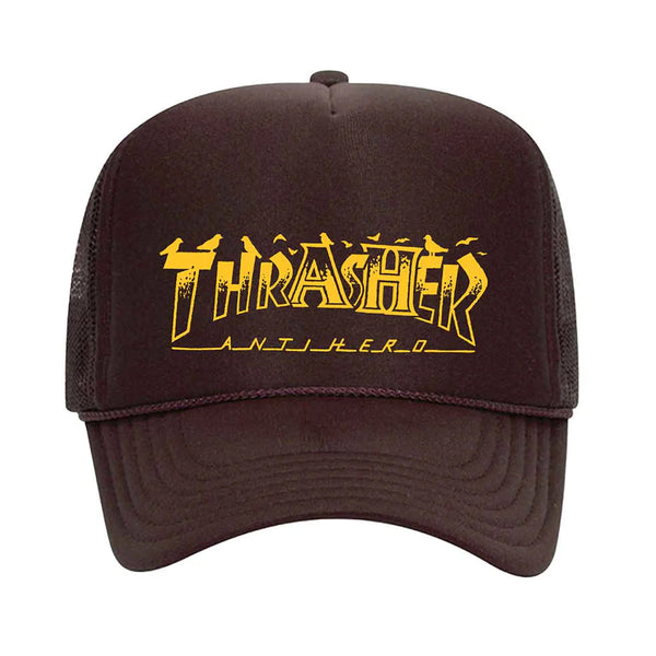 Brown mesh adjustable snapback hat with vibrant yellow "THRASHER x ANTI HERO PIGEON MAG TRUCKER HAT BROWN" logo artwork on the front by THRASHER.