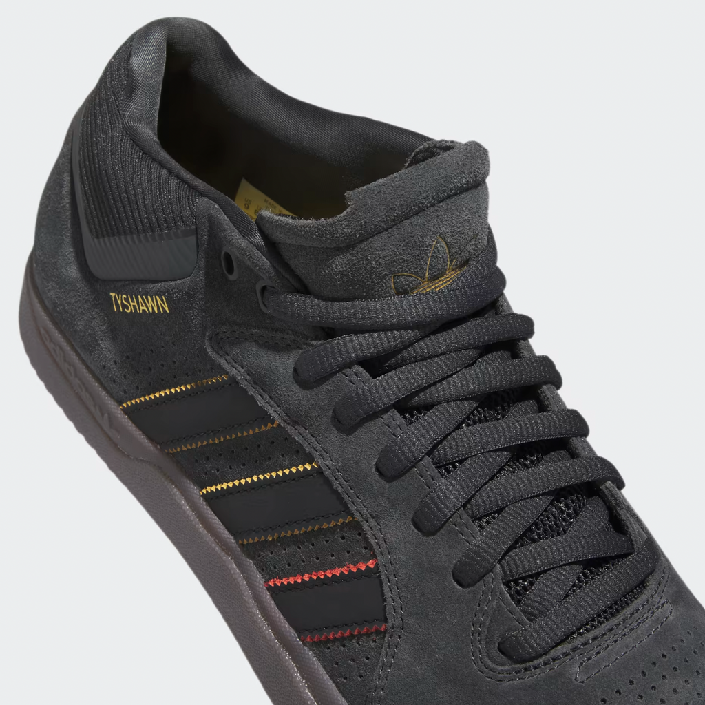 A pair of black and gold ADIDAS TYSHAWN CARBON / CORE BLACK / PRELOVED BROWN shoes.