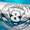 Close-up of a metallic logo reading "NEW V8 ADJUSTABLE WHEELBASE THE CHOICE IS YOURS," spotlighting VENTURE V8 TEAM EDITIONS 5.2 HI POLISHED skateboard trucks, with a blue blurred background emphasizing the innovative VENTURE design.