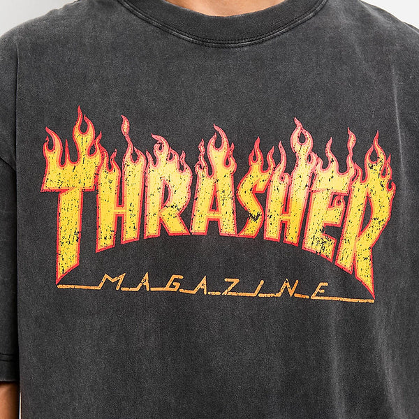 Close-up of the THRASHER FLAME VINTAGE TEE BLACK, a black boxy-fit tee by THRASHER featuring the iconic yellow and red "Thrasher Magazine" flame-style logo boldly across the front.