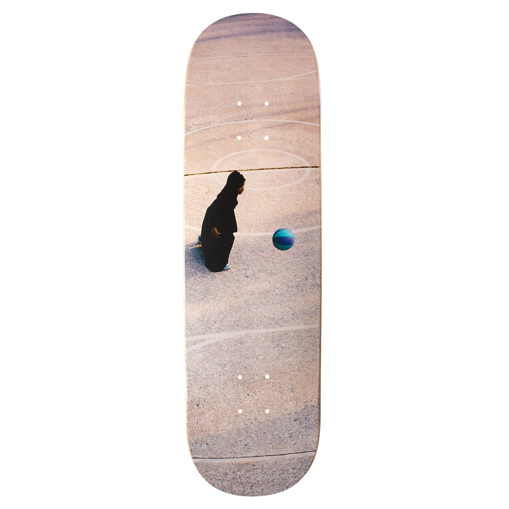 Introducing the VIOLET KADER "GIRL IN KHUMAR PLAYING BASKETBALL" skateboard deck by violet, showcasing a black-robed figure on concrete as she gazes at a vibrant blue and green basketball. Enhanced with blue metallic foil details, this design seamlessly blends mysterious allure with modern flair.