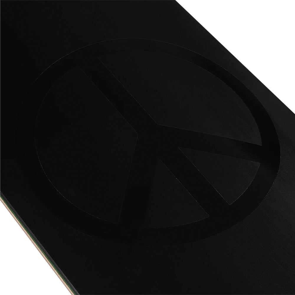 A close-up of a black surface with a subtle, embossed peace symbol, echoing the signature style of the violet VIOLET PEACE (PSALM 91) BLACK/BLACK skateboard.