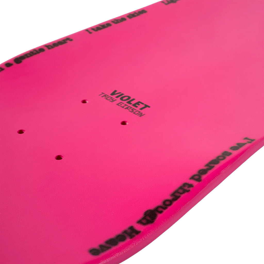 Close-up of the VIOLET TROY PRO MODEL NUMBER 2 PINK skateboard deck by violet, featuring a Sage Thomas graphic. The design includes black text with "Violet" and "Trex Gibson," along with visible holes for mounting trucks and additional text, highlighting the distinctive VIOLET TROY PRO design.