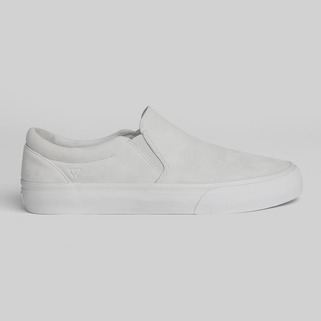 The STRANGER SLIP-ON | WHITE / WHITE by WARSAW LTD features a minimalistic, classic skate-inspired design with an all-white slip-on silhouette and rubber sole, showcased against a plain light gray background.
