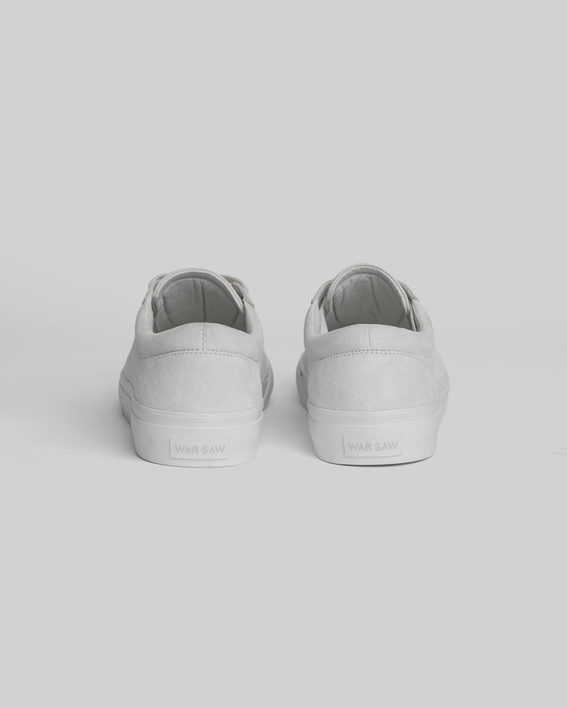A pair of CHAPTER | WHITE / WHITE sneakers by WARSAW LTD viewed from the back, showcasing the brand name on the heel tabs against a plain light background, with a minimalistic silhouette for effortless style.