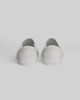 The STRANGER SLIP-ON sneakers by WARSAW LTD in white are shown from the back, highlighting their minimalistic silhouette against a plain light background.