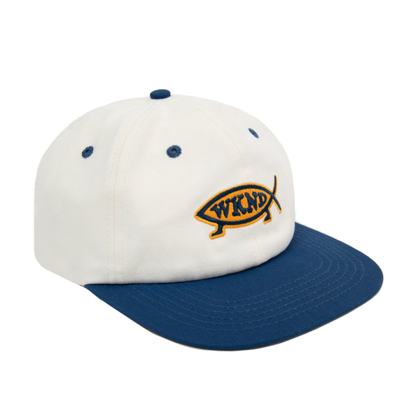 A white and blue WKND EVO FISH NATURAL / NAVY hat with a logo on it, made of brushed cotton.