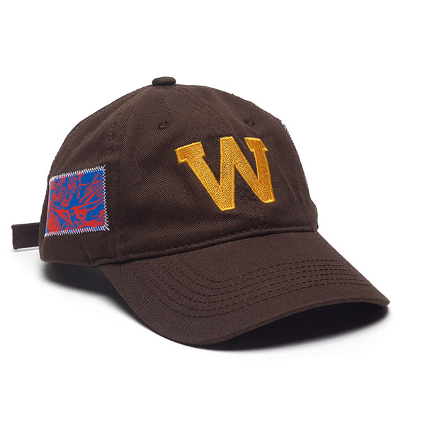 The WKND EDDY HAT BROWN by WKND features a bold yellow "W" embroidered on the front and a blue and red rectangular patch on the side.