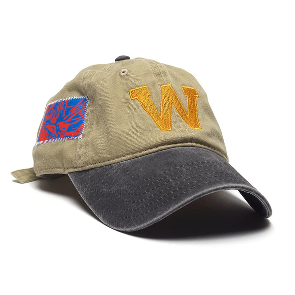 The WKND EDDY HAT KHAKI by WKND features a khaki crown with a yellow embroidered "W" on the front, a blue and red side patch, and a curved black brim.