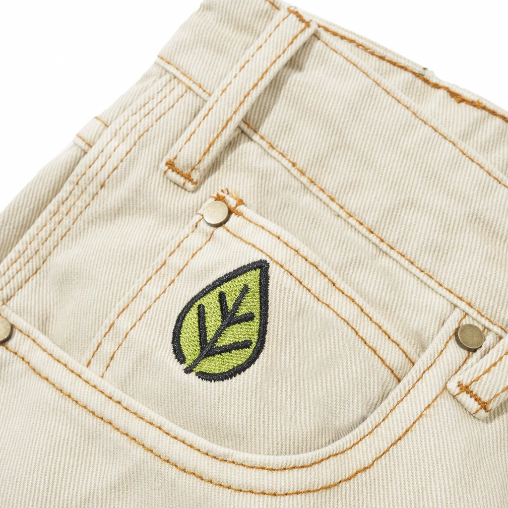 Close-up of the back pocket of Butter Goods Weathergear Heavy Weight Denim Jeans in washed khaki, showcasing yellow stitching and a green leaf embroidery on the pocket, with a baggy fit inspired by Butter Goods.