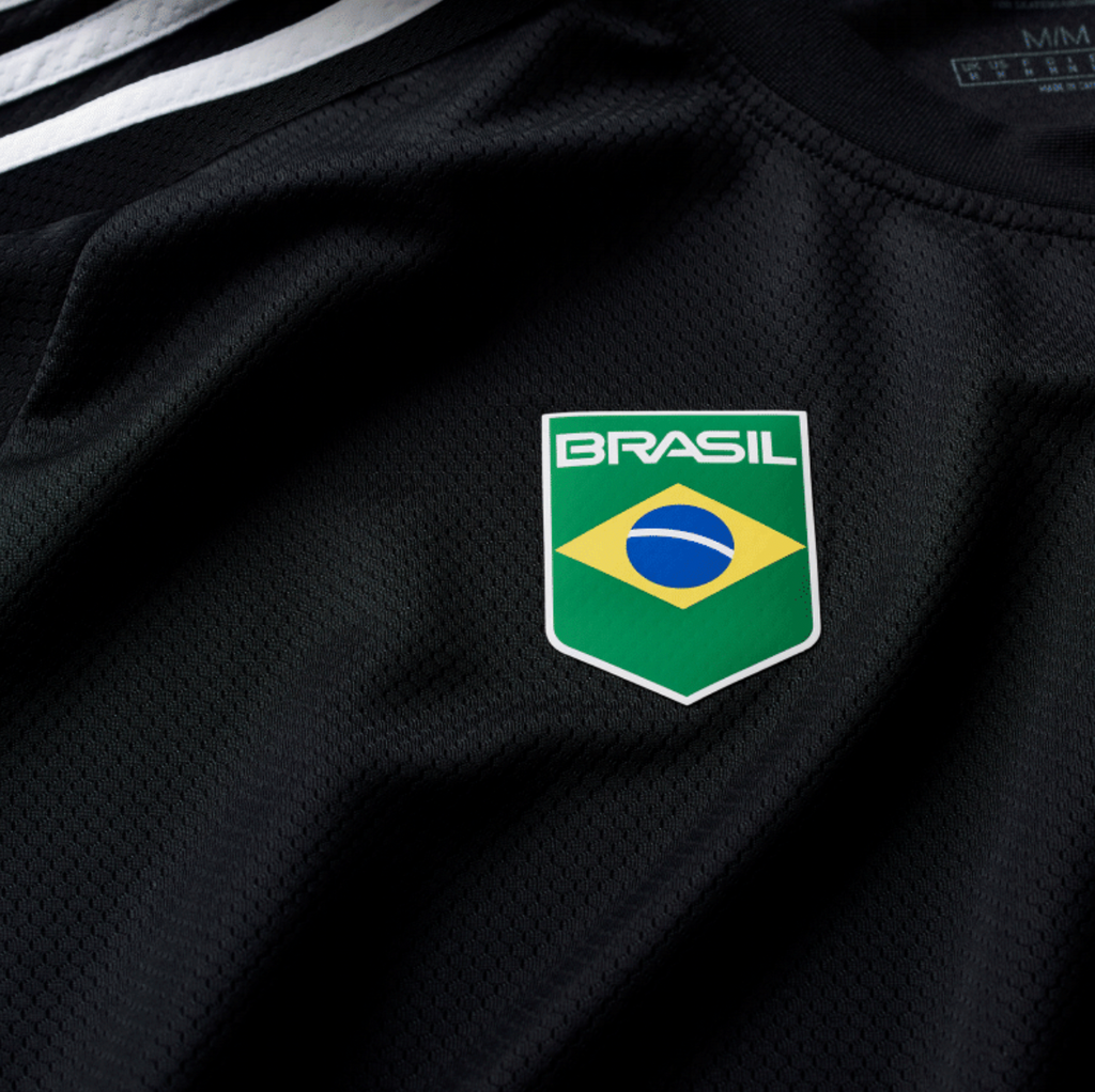 The ADIDAS SKATEBOARDING BRASIL AEROREADY JERSEY BLACK features a "Brasil" logo with the Brazilian flag emblem on the chest and is crafted from 100% cotton.