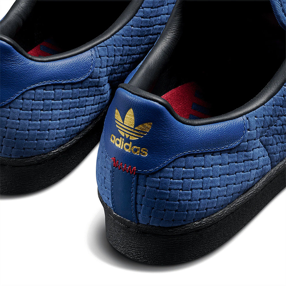 Close-up of the heel on the ADIDAS X ARROW & BEAST SUPERSTAR ADV NIGHT MARINE / CORE BLACK, showing woven blue texture, gold ADIDAS logo, red lining, and a durable black cupsole.
