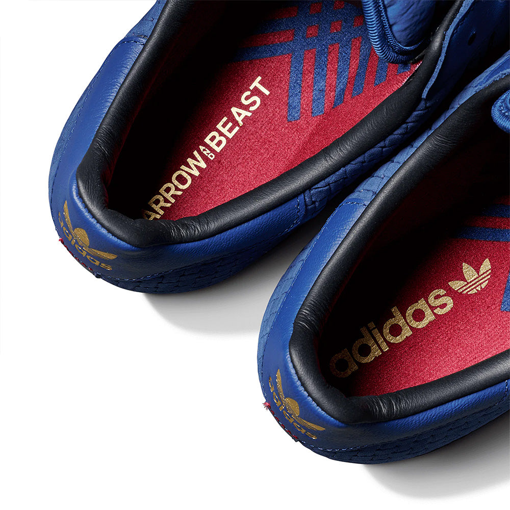 Close-up of the ADIDAS X ARROW & BEAST SUPERSTAR ADV NIGHT MARINE / CORE BLACK skate shoe, featuring red insoles with gold adidas and ARROW & BEAST branding, blue patterned detail, and a durable cupsole.