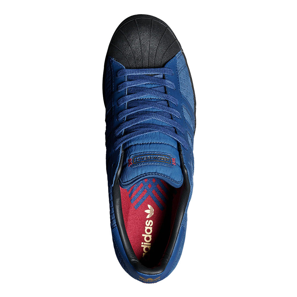 Top view of the ADIDAS X ARROW & BEAST SUPERSTAR ADV in Night Marine/Core Black, featuring a black toe cap, blue laces, and a red insole with a white Adidas logo; classic cupsole nods to its Superstar ADV heritage.