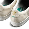 Close-up of the heel area on ADIDAS X ARROW & BEAST SUPERSTAR ADV WONDER WHITE / CRYSTAL WHITE, featuring a woven texture, gold adidas logo, green stitching, and a patterned green insole.