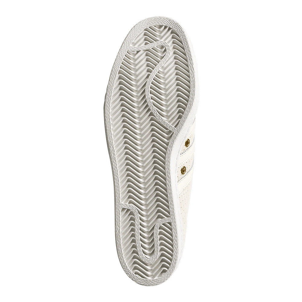 The ADIDAS X ARROW & BEAST SUPERSTAR ADV in Wonder White/Crystal White is shown sole-up, revealing its cupsole construction and laces artfully placed on the sole to outline a foot.
