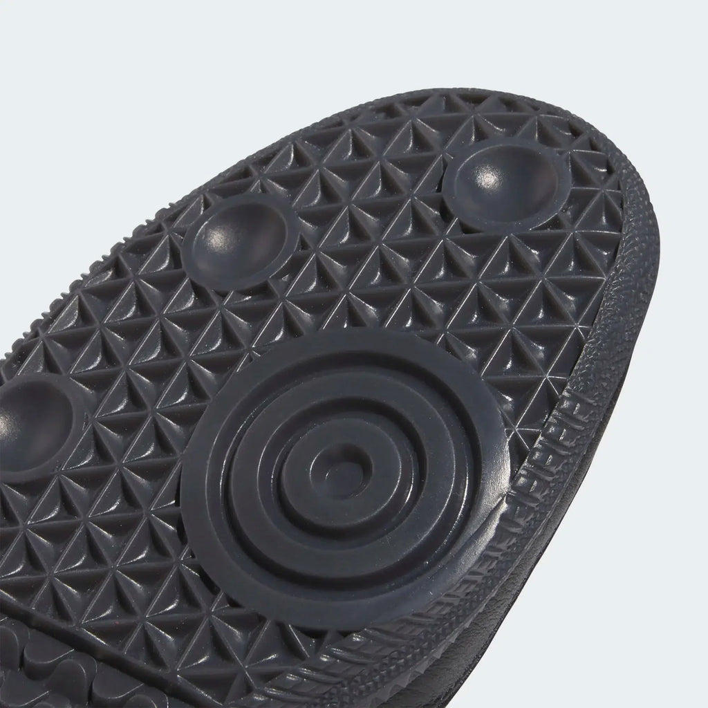 Close-up view of the textured sole of an ADIDAS X CLTFC X BLACK SHEEP SAMBA ADV in Core Black/Cloud White/Ice Blue, featuring circular and triangular patterns for grip and stability.