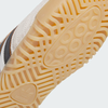 Close-up of the yellow rubber sole on the ADIDAS BUSENITZ INDOOR SUPER BLISS / CORE BLACK / OFF WHITE, showing detailed circular and geometric tread patterns with the iconic Adidas logo—a modern skateboarding essential.