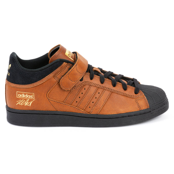 A single ADIDAS PRO SHELL ADV X HEITOR DARK BROWN / CORE BLACK sneaker featuring a brown leather upper with gold accents and signature stripes, isolated on a white background.