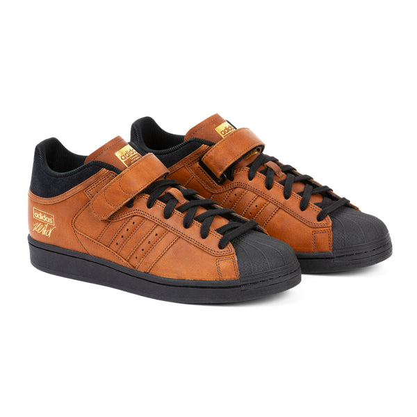 A pair of brown ADIDAS PRO SHELL ADV X HEITOR sneakers with black accents and laces, isolated on a white background.