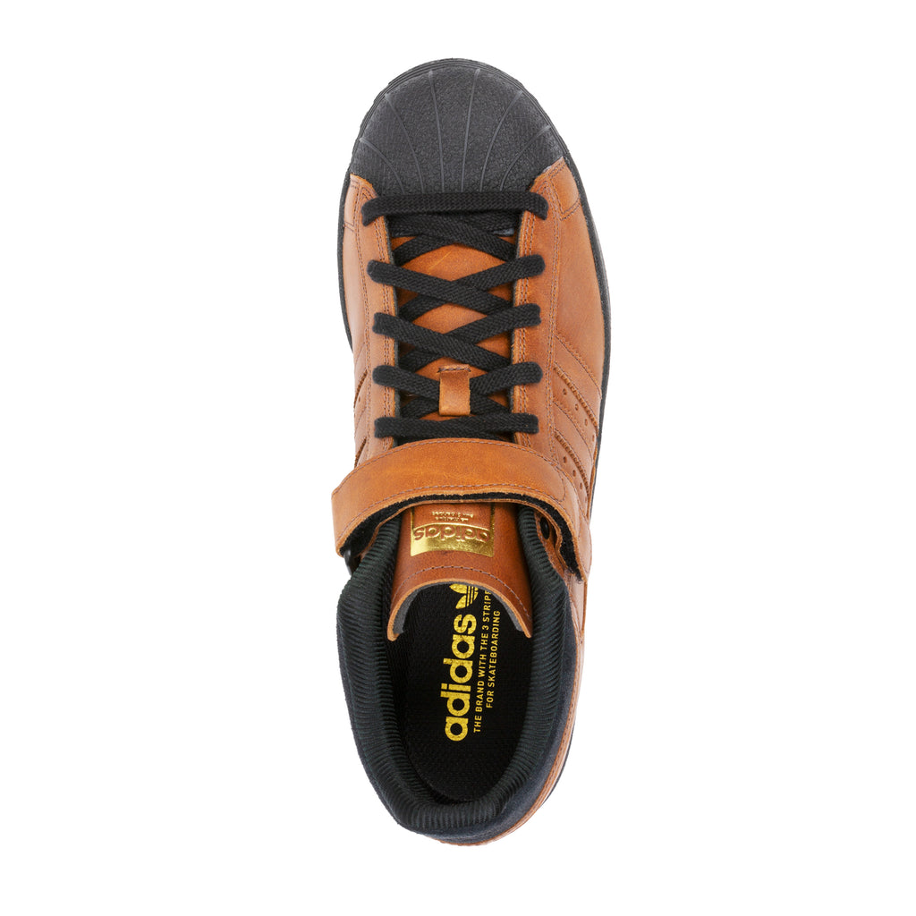 Top view of a brown ADIDAS PRO SHELL ADV X HEITOR sneaker with Core Black laces and a visible logo on the tongue.
