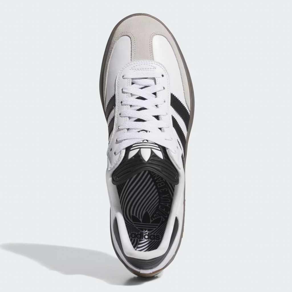 Top view of a white ADIDAS Puig Samba ADV Cloud sneaker featuring Core Black stripes, a light grey suede toe cap, an EVA midsole for comfort, and a patterned insole with the Adidas logo.