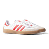 A pair of classic Adidas Puig Samba sneakers in Flat White with Better Scarlet stripes and Gum soles, featuring a cushioned EVA midsole for supreme comfort.