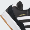 The Adidas Tyshawn 2 in Core Black/Cloud White/Gum boasts a black and white design with a gum sole. "Tyshawn" is elegantly displayed in gold on the side, and its impact cushioning ensures top comfort for both skating and casual wear.