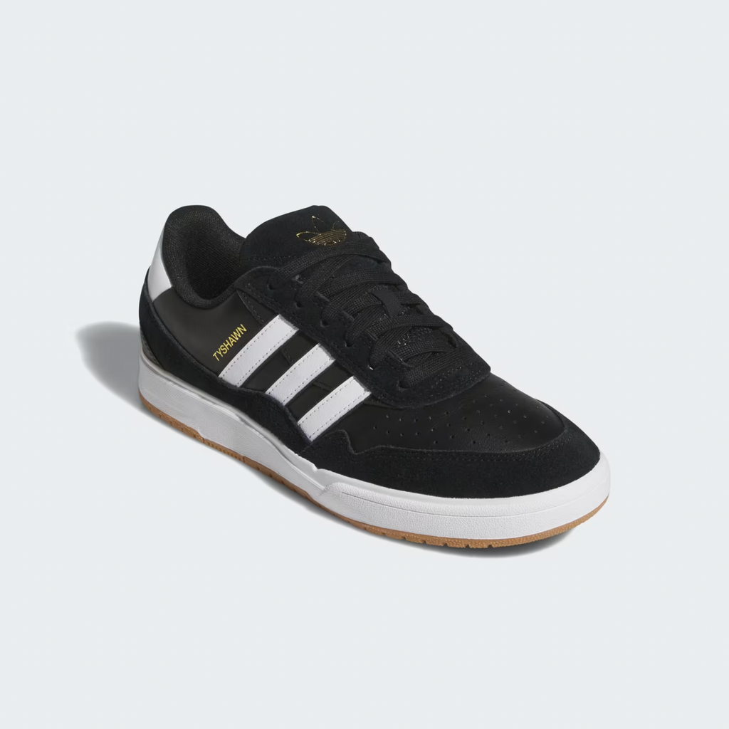 The ADIDAS TYSHAWN 2 CORE BLACK / CLOUD WHITE / GUM sneaker features white stripes, a gum sole, and gold "Tisukuri" text. Inspired by Tyshawn Jones, these skateboarding shoes combine style and performance.