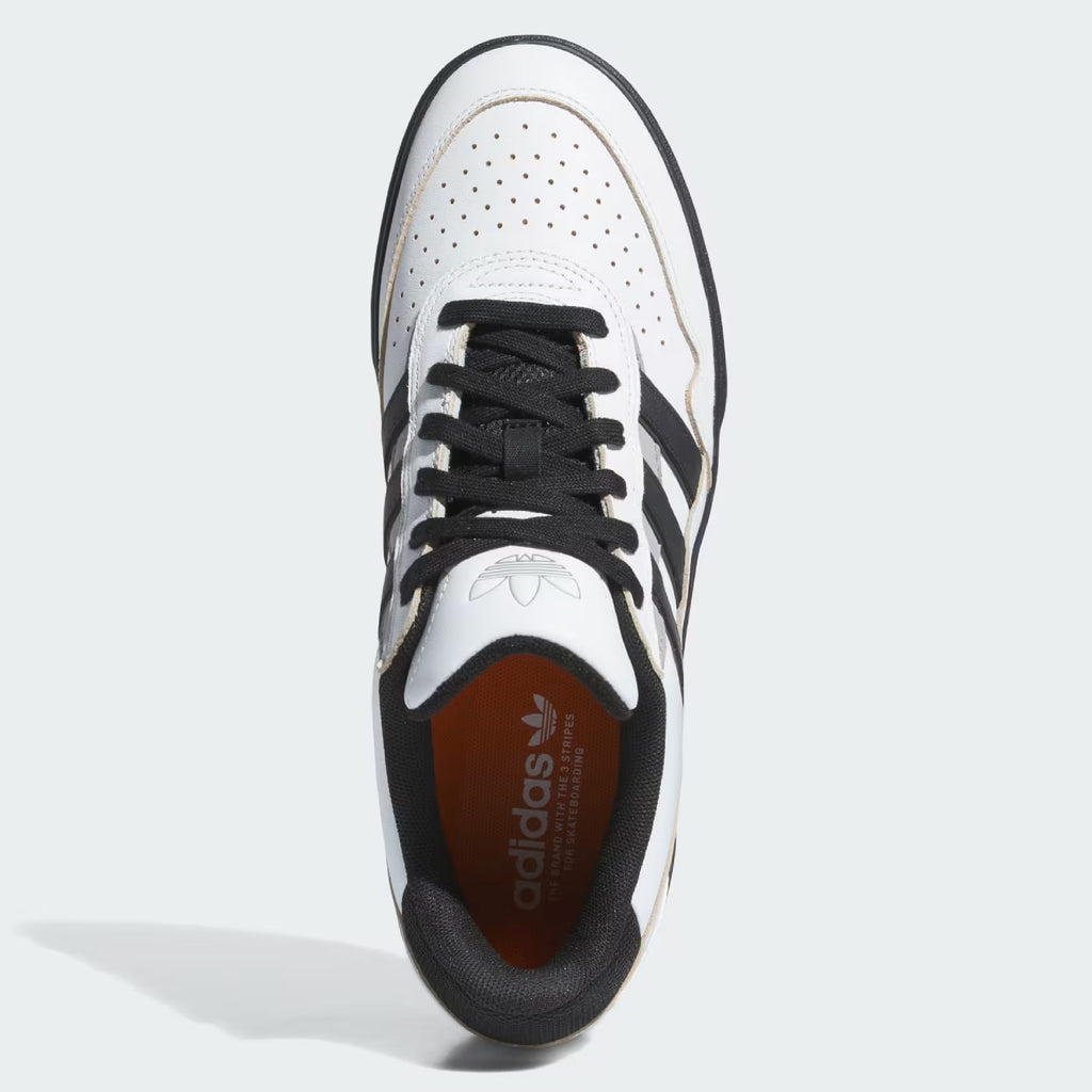 Top view of the ADIDAS TYSHAWN 2 CRYSTAL WHITE / CORE BLACK / CHARCOAL SOLID GREY shoe, featuring a perforated toe box, black laces, and three black stripes on the sides. The inner sole is orange with white ADIDAS branding.