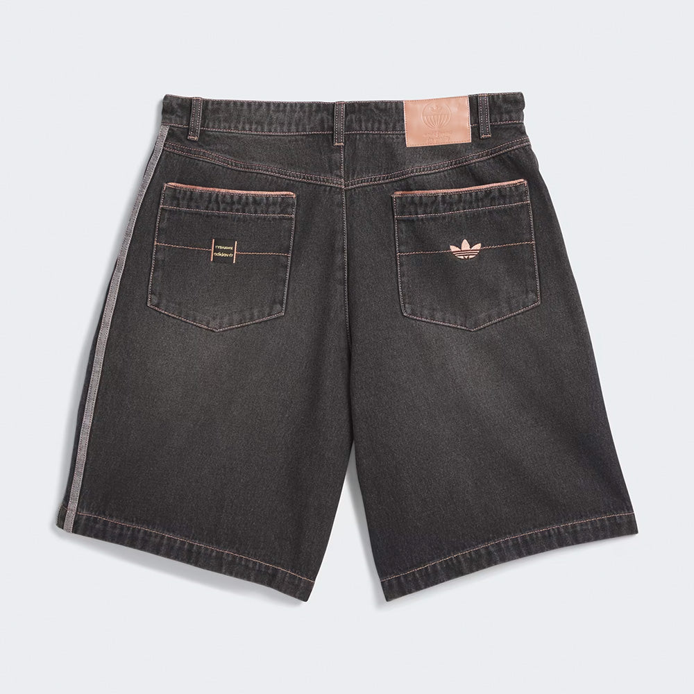 Back view of the ADIDAS SKATEBOARDING TYSHAWN DENIM SHORT in black 100% cotton, featuring two rear pockets—one with a stitched emblem, one with an ADIDAS logo—and a tan logo patch on the waistband, designed for skateboarding style.
