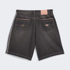 Back view of the ADIDAS SKATEBOARDING TYSHAWN DENIM SHORT in black 100% cotton, featuring two rear pockets—one with a stitched emblem, one with an ADIDAS logo—and a tan logo patch on the waistband, designed for skateboarding style.