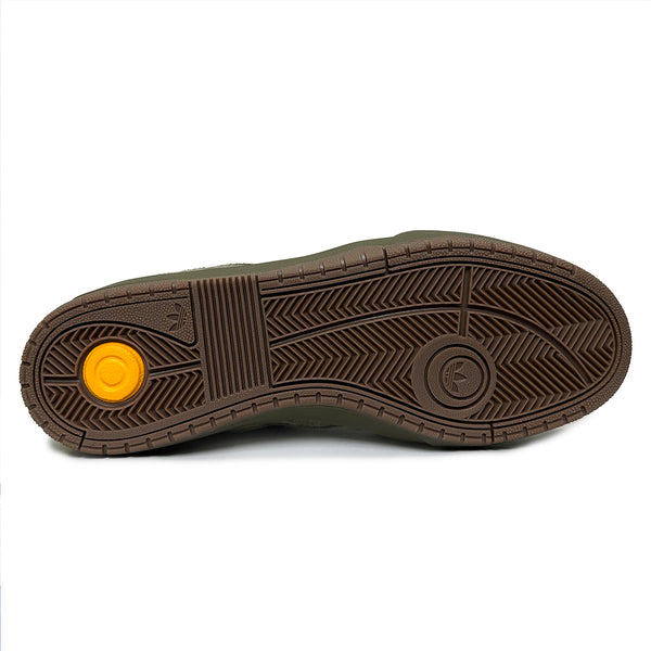 The ADIDAS TYSHAWN 2 OLIVE / GUM features a brown rubber sole with varied tread patterns, a yellow circular detail near the heel, and a logo by the forefoot, showcasing its durable cupsole typical of ADIDAS skate shoes.