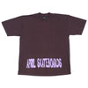 a brown shirt with purple spray paint letters spell out april skateboards on the shirt near the bottom stitch