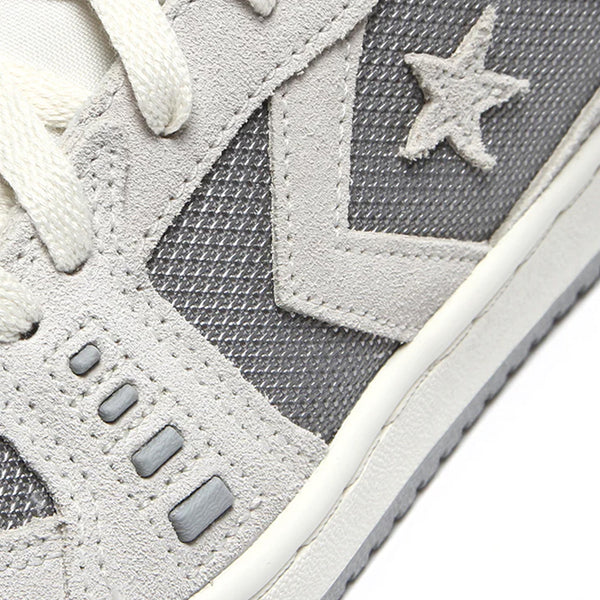 Close-up image of the CONVERSE CONVERSE CONS ALEXIS AS-1 PRO VAPOROUS GRAY / GREY AREA skateboarding shoe, designed by Alexis Sablone, featuring a star and arrow design on the grey and white sneaker.