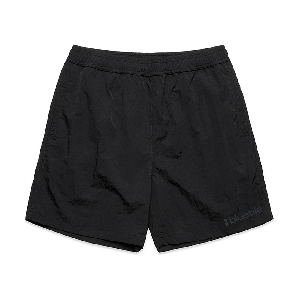 BLUETILE LOGO SWIM SHORTS BLACK by Bluetile Skateboards feature quick-dry recycled nylon, an elastic waistband, and a small BLUETILE LOGO on the lower left leg, shown on a white background.