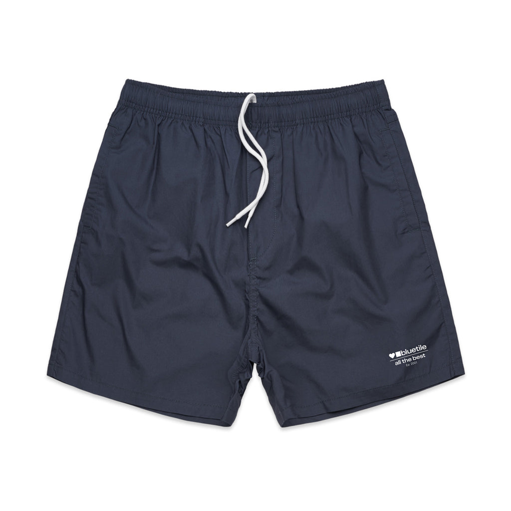 BLUETILE SURPLUS V3 BEACH SHORT PETRO BLUE by Bluetile Skateboards features an elastic waistband with a white drawstring and a small white logo on the left leg.