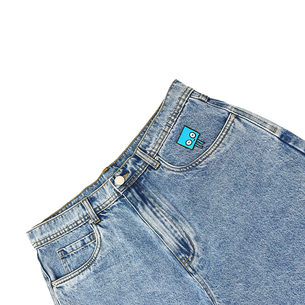 BLUETILE BRAND DENIM RUTLEDGE JORTS BLUE by Bluetile Skateboards: light blue, loose-fit denim jorts with a cartoon face blue patch above the front pocket, shown on a white background.
