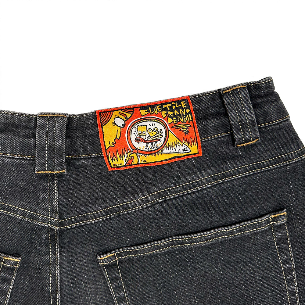 Back view of the BLUETILE BRAND DENIM RUTLEDGE PANT BLACK by Bluetile Skateboards, featuring a colorful embroidered "BLUETILE CANNA DENIM" patch with cartoon graphic above the waistband.