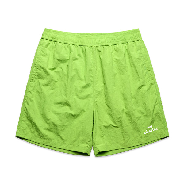 A pair of bright green "BLUETILE LOGO SWIM SHORTS CITRUS" from Bluetile Skateboards, made of cotton with an elastic waistband and the "BLUETILE SURPLUS V2" logo on the left leg, perfect for the beach.