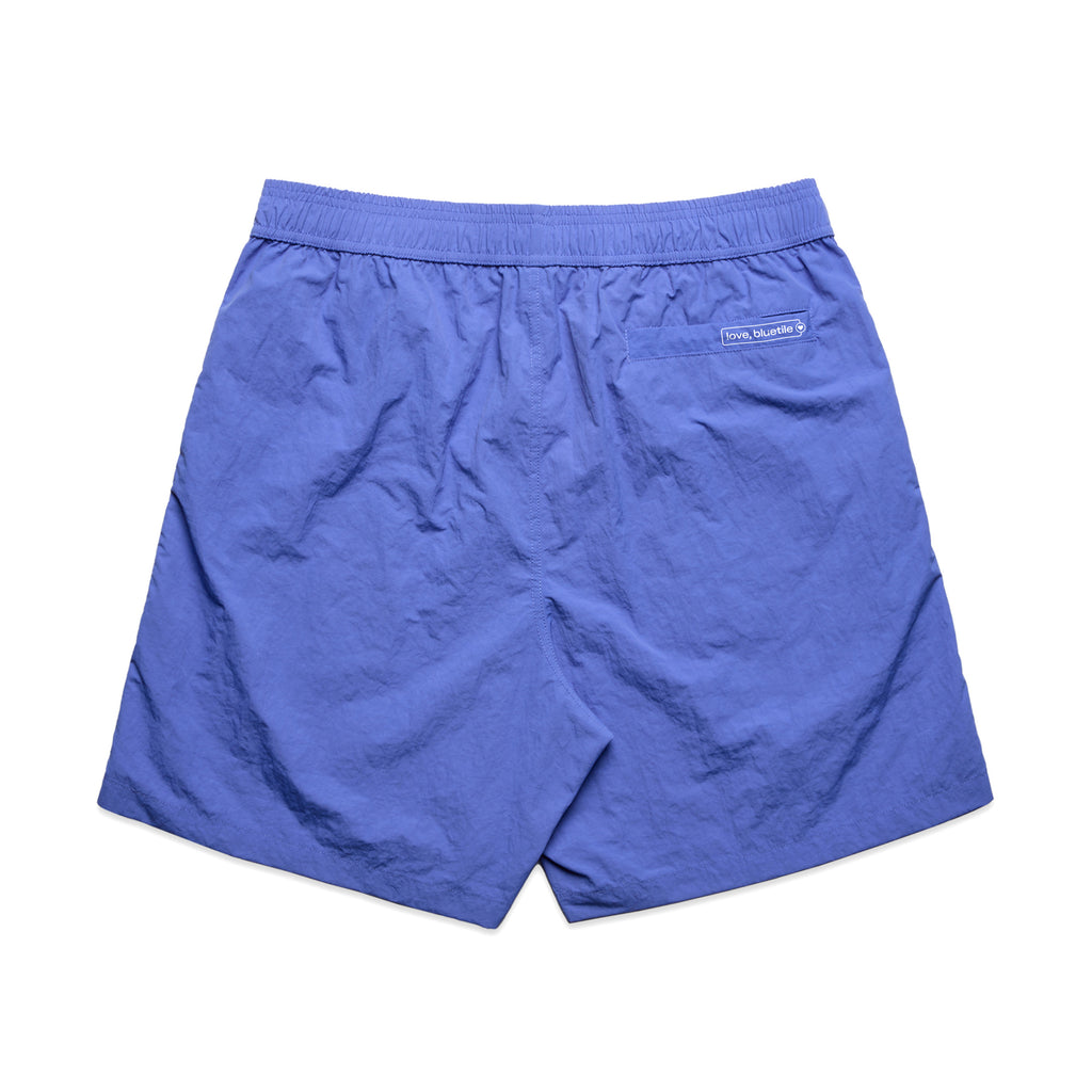 A pair of BLUETILE LOGO SWIM SHORTS LAPIS by Bluetile Skateboards with an elastic waistband, crafted from recycled nylon. These quick-dry fabric shorts feature a small logo on the back right side.